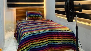 A bedroom with a bed, a fan, and a window with horizontal blinds. - Flenjo Zone Bar and Apartments (Ado Ekiti)