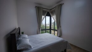 A bedroom with a large window, a bed, and a nightstand. - Lake Victoria View 1 Bedroom Apartment Entebbe (Entebbe)