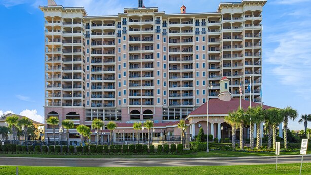 A multi-story hotel with balconies, a central entrance, and palm trees in the foreground. - Spacious 2nd row condo, great amenities + Free Attraction Tickets! (North Myrtle Beach)