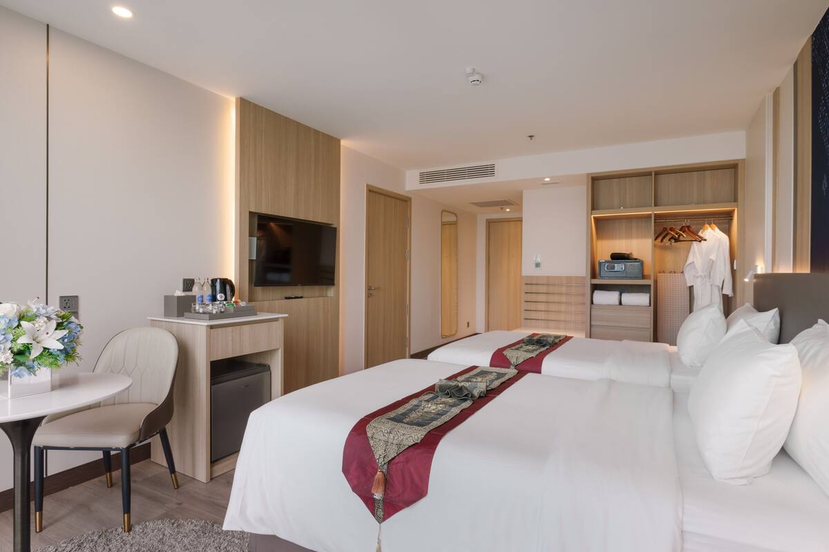 A hotel room with a bed, a desk, a chair, a small kitchenette, and a walk-in closet.