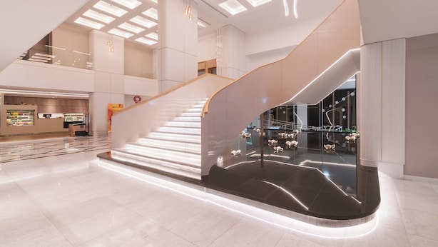 Een modern interieur met een gebogen trap, inbouwverlichting en een glazen balustrade.