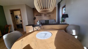 Uma sala de jantar com uma mesa redonda de madeira, um sofá e um lustre.
