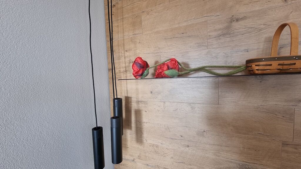 Ein Holzboden mit einem gewebten Korb und getrockneten roten Blüten.