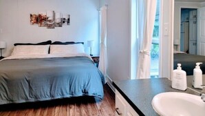 Ein Schlafzimmer mit einem Bett, Nachttischen, einem Spiegel und einem Fenster mit Vorhängen.