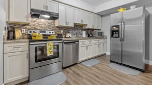 Een moderne keuken met witte kasten, roestvrijstalen apparatuur en een houten vloer.