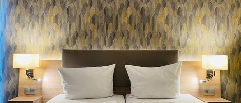Ein Hotelzimmer mit einem großen Bett, zwei Nachttischlampen und einer Wand mit Muster.