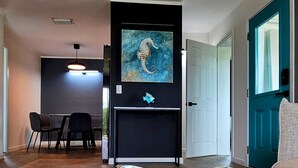 A modern living room with a unique teal and white decorative bowl centerpiece, a flat-screen TV mounted on a black stand, and a teal door. - Luxury beach villa in paradise. (Treasure Cay)