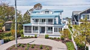 Une maison à deux étages avec un porche, une véranda couverte à l’avant et un petit jardin devant.
