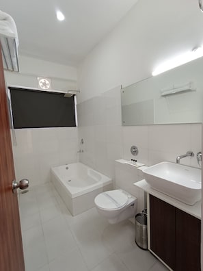 A modern bathroom with a bathtub, toilet, and sink. - Gezellig Inn Oasis (Kullu)