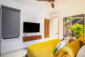 A bedroom with a bed, a mounted TV, a ceiling fan, and a door. - Modern Luxury 2BR in Romantic Zone (Puerto Vallarta)