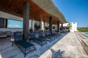 A poolside area with lounge chairs and a view of the sea. - Modern Luxury 2BR in Romantic Zone (Puerto Vallarta)
