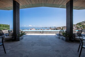 An outdoor seating area with chairs and planters, overlooking a coastal cityscape. - Modern Luxury 2BR in Romantic Zone (Puerto Vallarta)