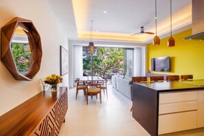 A modern kitchen with a dining area, a large window, and a TV.