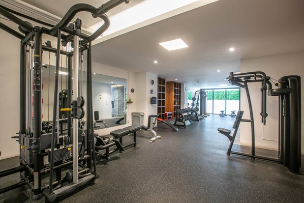 A gym with various exercise equipment, a bench, and a mirrored wall. - Modern Luxury 2BR in Romantic Zone (Puerto Vallarta)