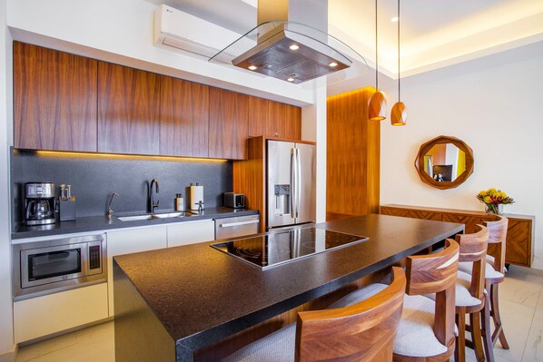 A modern kitchen with a central island, stainless steel appliances, and wooden cabinetry. - Modern Luxury 2BR in Romantic Zone (Puerto Vallarta)