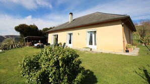 A single-story house with a sloped roof, a covered patio, and a well-maintained lawn. - Krys Chambre vue sur les Pyrenees et le pis du Midi (Bagnères-de-Bigorre)