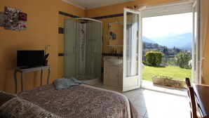 A bedroom with a bed, a TV, a shower, and a bathroom with a sink and mirror. - Krys Chambre vue sur les Pyrenees et le pis du Midi (Bagnères-de-Bigorre)