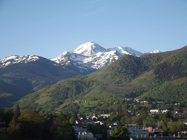 Una montaña con picos nevados, un pueblo con casas y colinas verdes exuberantes.