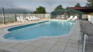 A swimming pool with white lounge chairs and a glass-enclosed structure. - Krys Chambre vue sur les Pyrenees et le pis du Midi (Bagnères-de-Bigorre)