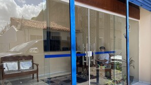 A modern building with large glass doors, a tiled floor, and a bench outside. - Hostel da Fonte (São Luís)