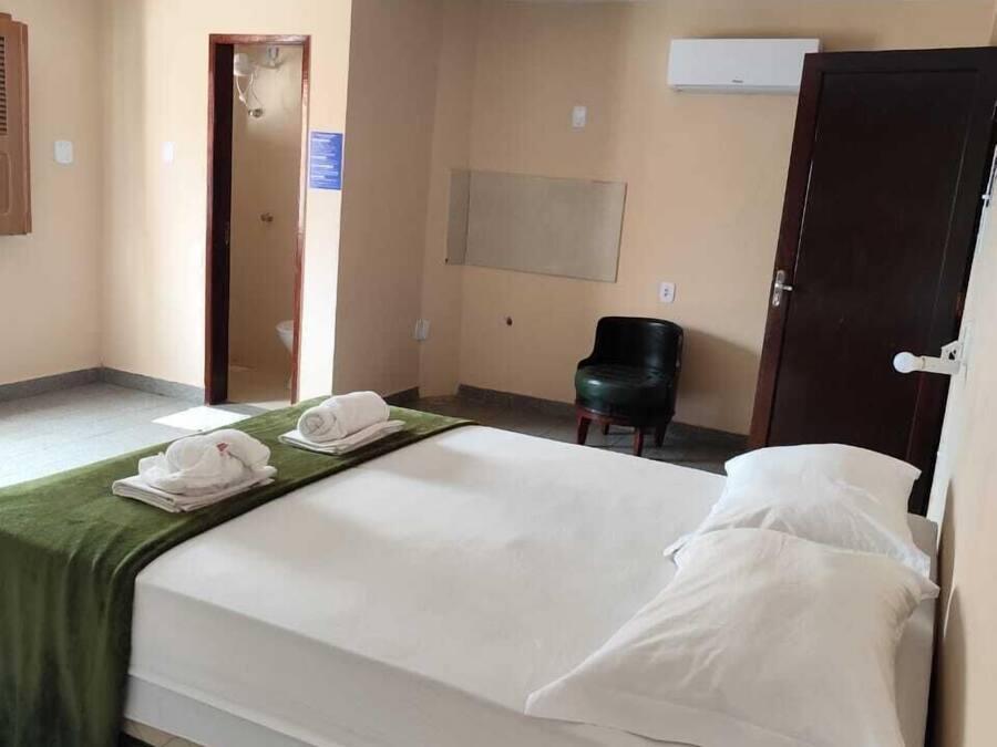 Una habitación de hotel con una cama, una silla, un escritorio y una puerta.