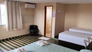 A room with two beds, a chair, a window with curtains, and an air conditioning unit. - Hostel da Fonte (São Luís)
