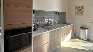 A modern kitchen with wooden cabinetry, a stainless steel sink, and a tiled backsplash. - Maison de Type Bergerie , Proximité Porto Vecchio - Www.casarella.eu (Zonza)