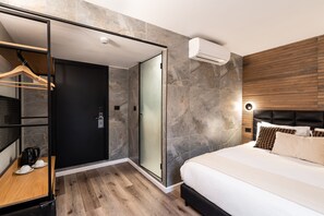 A modern hotel room with a bed, a walk-in closet, and a shower area. - Mulan TLV Hotel (Tel Aviv)