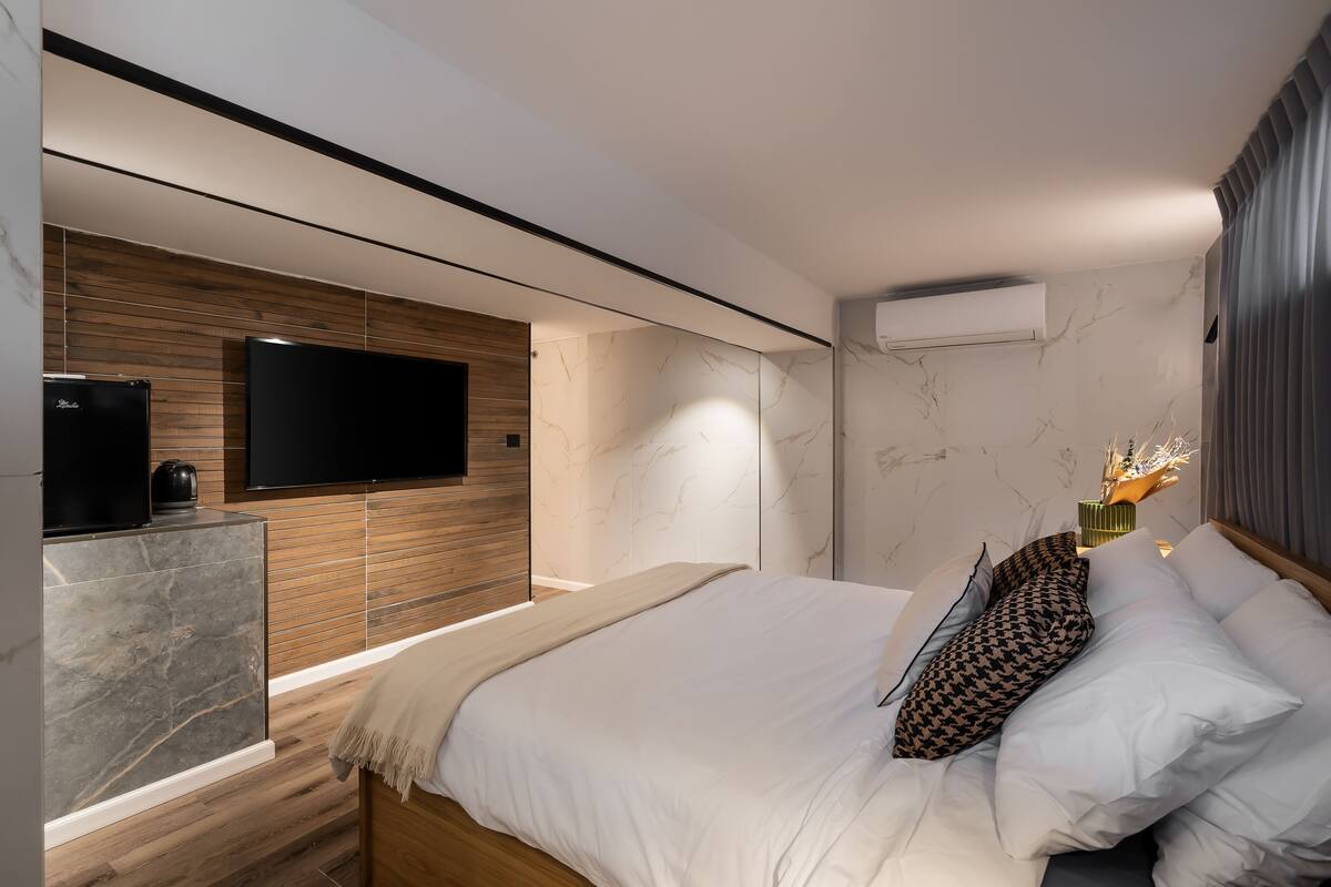 A modern bedroom with a large bed, a flat-screen TV, and a built-in wardrobe.