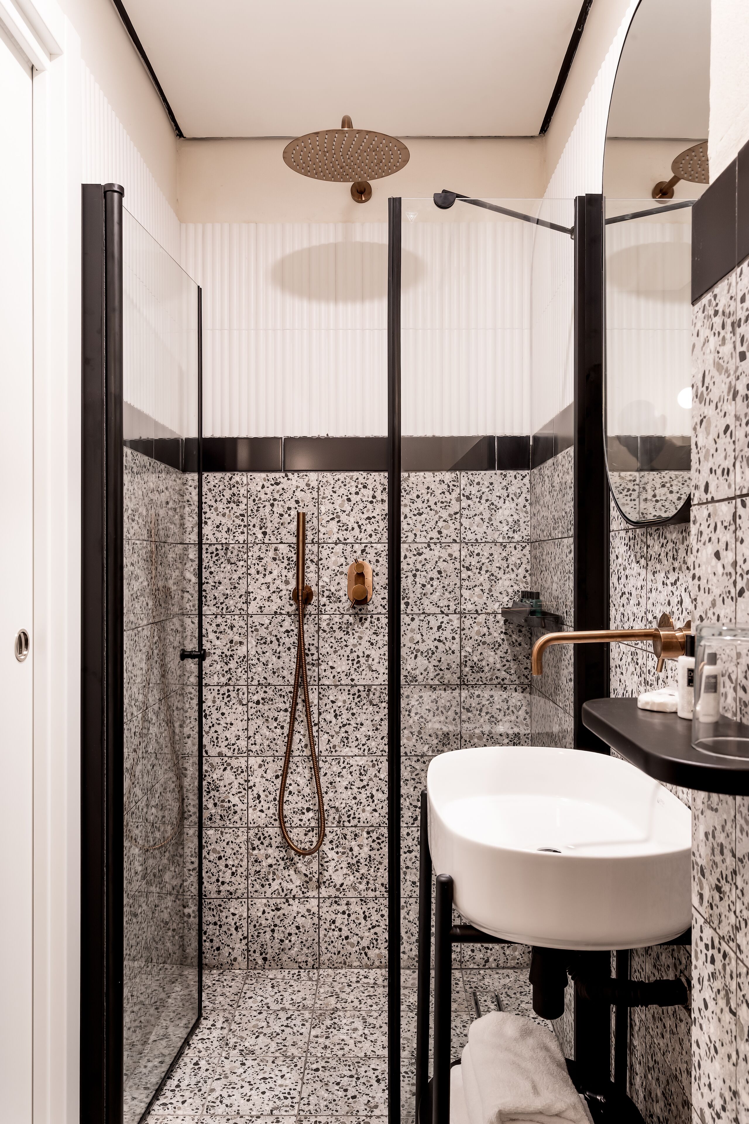 A modern bathroom with a glass-enclosed shower, a white sink, and a black countertop.