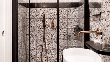 A modern bathroom with a glass-enclosed shower, a white sink, and a black countertop.
