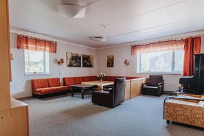 Una sala de estar con sofá, sillones, una mesa y un piano.