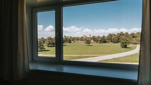 Vista a través de una ventana de un área con césped, un edificio y árboles.