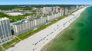 Un hotel costero con varios edificios altos, una extensa playa y una vista despejada del océano.
