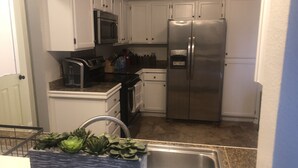 A kitchen with white cabinets, stainless steel appliances, a microwave, a stove, and a refrigerator.