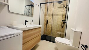 A modern bathroom with a white sink, wooden vanity, and a glass-enclosed shower area. - Sunset Dream Suite El Cotillo (El Cotillo)