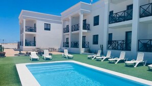 Ein modernes Hotel mit Pool, weißen Wänden und Balkonen.
