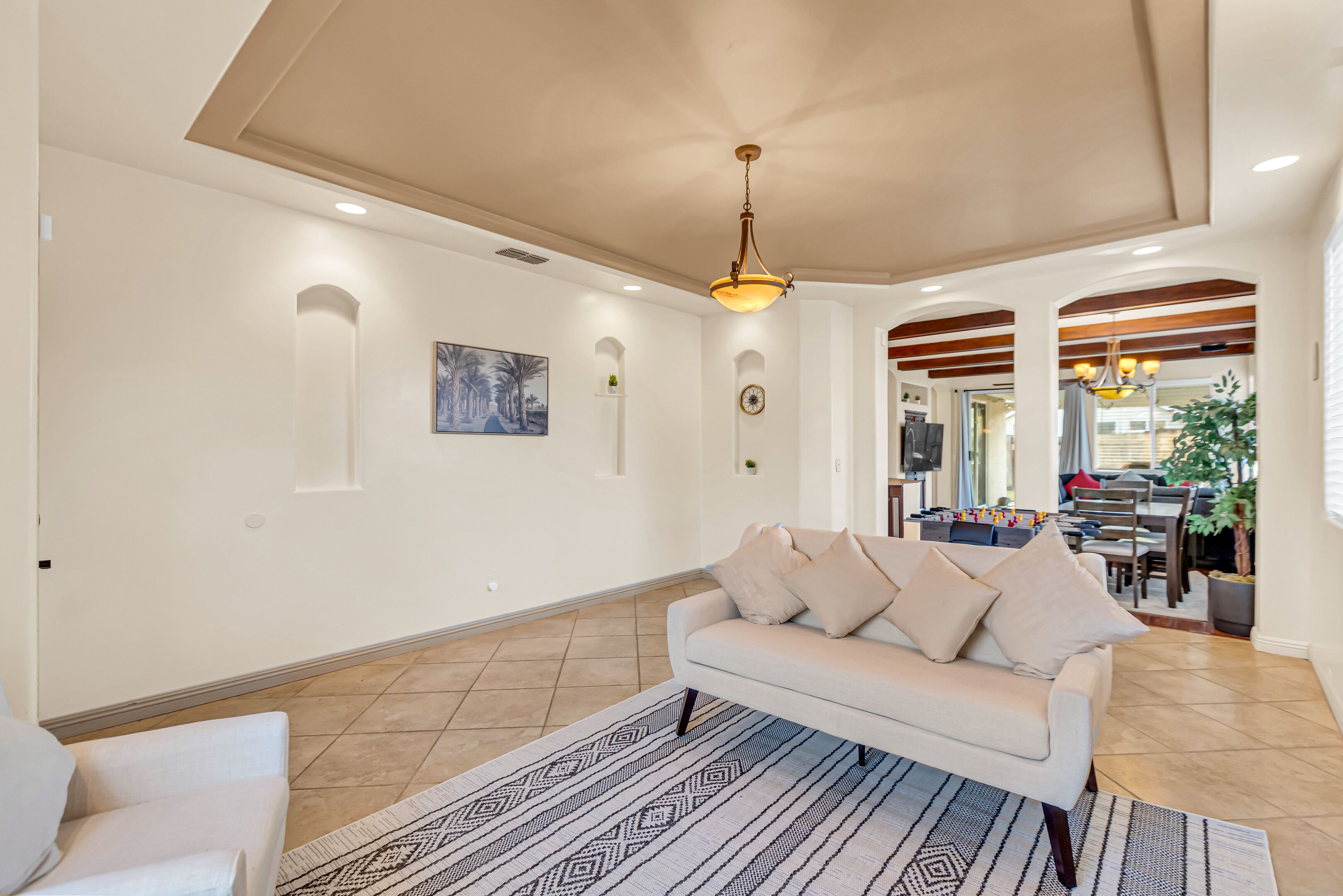 Un soggiorno ampio con un divano color beige, un tappeto decorato e una ventola a soffitto.