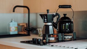 A kitchen with wooden cabinets, a coffee maker, a kettle, and a sink.