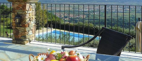 Zona de piscina con un pilar de piedra, una cesta de mimbre con fruta y vistas a una zona residencial.