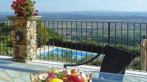 A balcony with a stone pillar, a wicker chair, and a fruit basket. - Estate in Monte Serra with Panoramic Views (Pisa)
