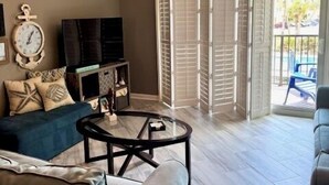 Una sala de estar con ventilador de techo, sofá, mesa de centro y televisor.