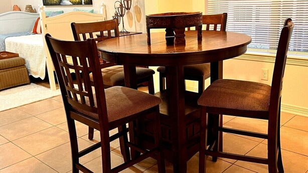 Uma área de refeições com uma mesa de madeira redonda e quatro cadeiras.
