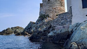 A coastal scene with a historic stone tower and a modern building with a balcony.