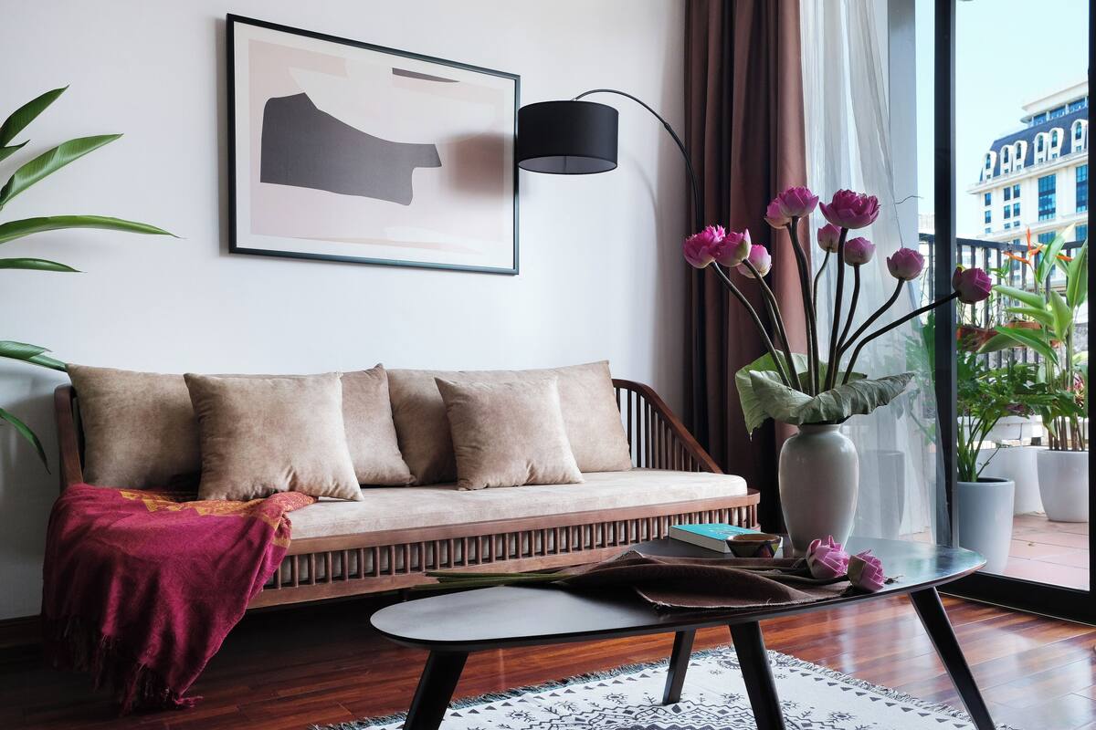 A modern living room with a sofa, a coffee table, a floor lamp, and a vase with flowers.