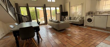 A spacious living area with a dining table, sofa, and a washing machine in the corner.