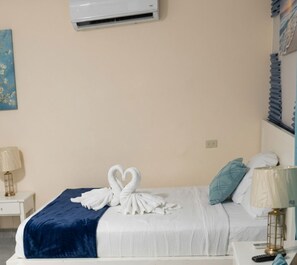 A hotel room with a bed, a wall-mounted air conditioner, a bedside lamp, and a decorative towel arrangement. - Sol Caribe Beach Group (Punta Cana)