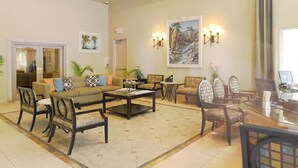 A spacious living room with a sofa, armchairs, a coffee table, and a dining area with chairs and a table. - Yess! Full Kitchen & Heated Pool w/waterfall! (Palm Springs)