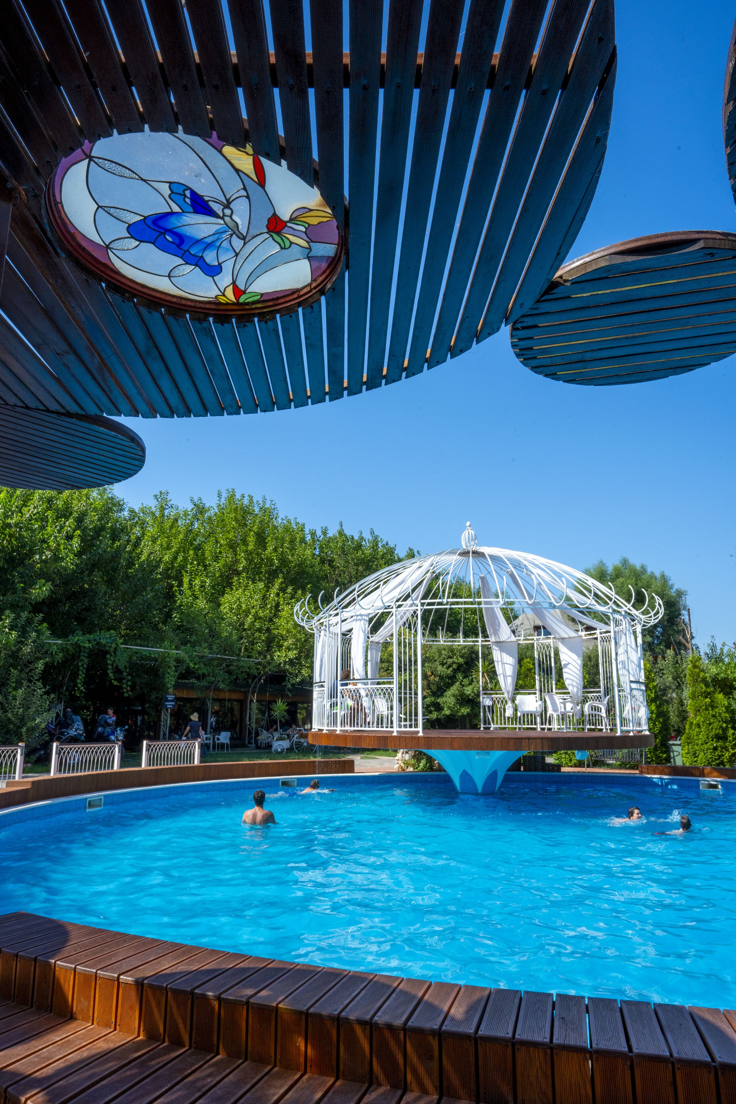 Una piscina con un pabellón, cubierta de madera y una vidriera.