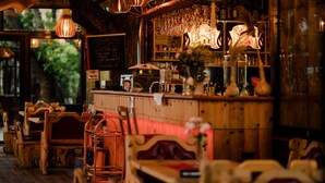 A rustic bar area with wooden furniture, a chalkboard menu, and hanging light fixtures. - Hotel Legjenda (Shkodër)